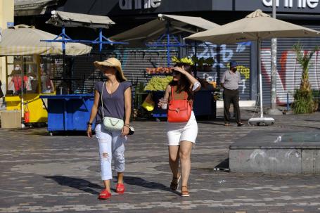 Women walk across a sunny street in Athens.