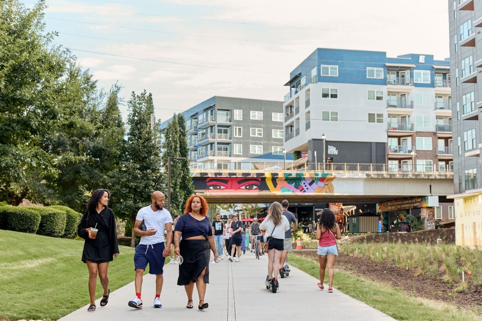 People walk along a paved walkway along the Atlanta Beltline.