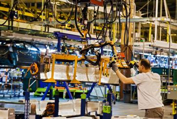 An autoworker moves a lithium-ion battery into position at a car manufacturing plant in Detroit.