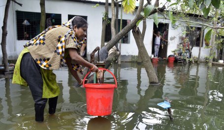 Woman pumps water on a flooded street in Dhaka, Bangladesh