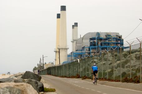A bicyclist rides past a factory in Manhattan Beach, California
