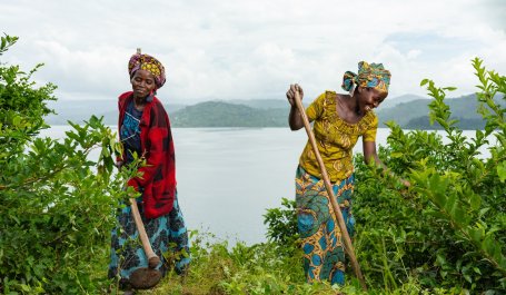 Two women tending plants and smiling.