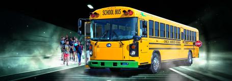 An electric bus picking up school children.