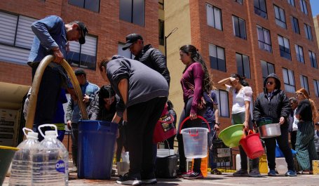 People stand in line with buckets for water rations.