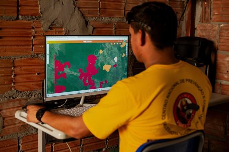 A man looks at maps on a computer showing where forest fires are burning.