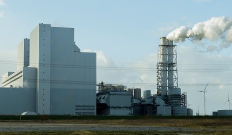 A power plant with wind mills and a smoke column in the center. 