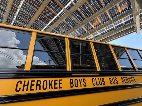 The side of an electric bus reads Cherokee Boys Club Bus Service
