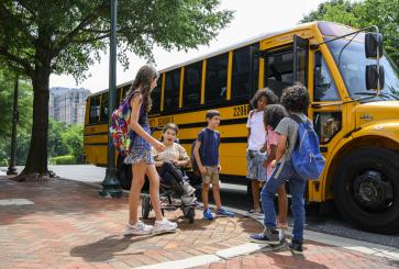 Children waiting in front of electric school bus