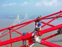 Workers on a power transmission tower overlooking a river.