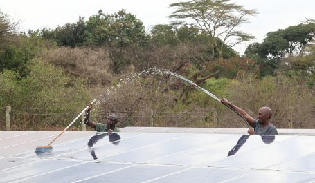 Two men clean solar panels in Kenya