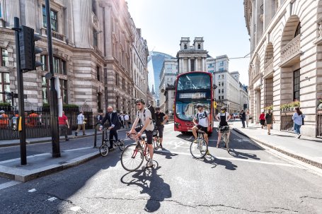 Cyclists and a red bus on a London street.