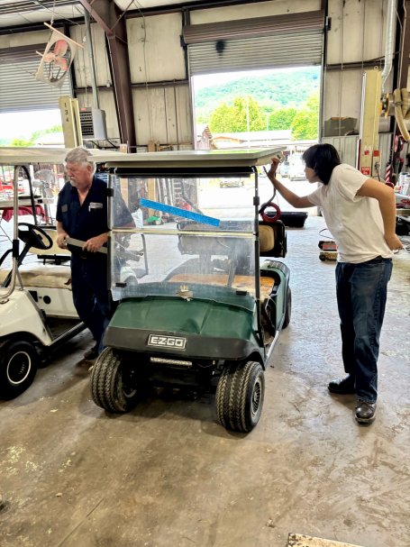 An instructor and student working on a solar-powered golf cart in an automotive garage. 