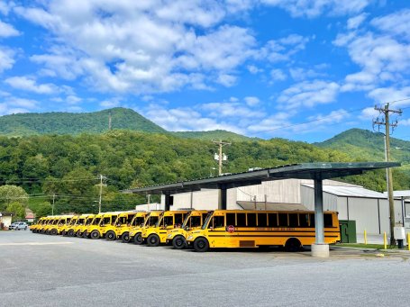 Electric school buses charging under a solar canopy.