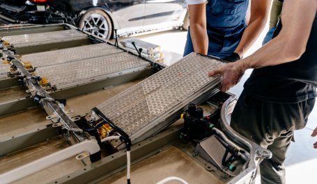 Auto workers install battery packs in the frame of an electric vehicle.