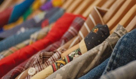 A close-up of multiple different colored button-ups on hangers. 
