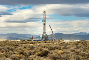  Geothermal drilling rig with power plant in background, Nevada, U.S.A.