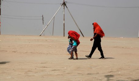 A family covers their heads with cloth for sun protection while walking near the Ganges river during a heatwave.