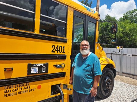 School bus driver Ron Reser next to an electric school bus used for Shawnee Public Schools