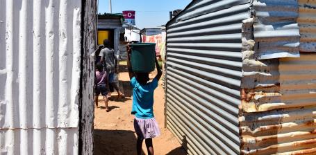 A young girl carries water through an informal settlement in Johannesburg, South Africa.