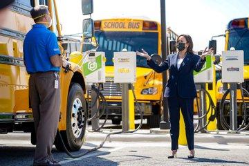 Vice President Kamala Harris surrounded by an electric fleet of school busses. 