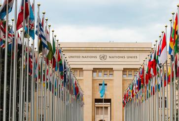 The front of the United Nations building lined with flags. 