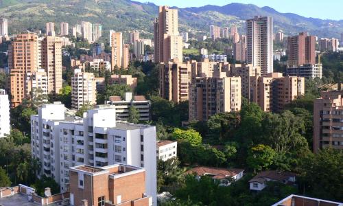 Aerial view of skyscrapers surrounded by lush trees lining city streets.