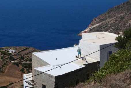 A man painting a rooftop white.