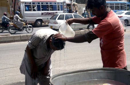 Water is poured over a man's head during his commute to beat the heat.