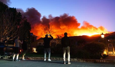 People take photos of a wildfire blazing over the L.A. hills.