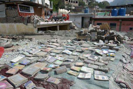 Piles of damaged books and other belongings are lined up in the dirt after flooding in Pakistan.