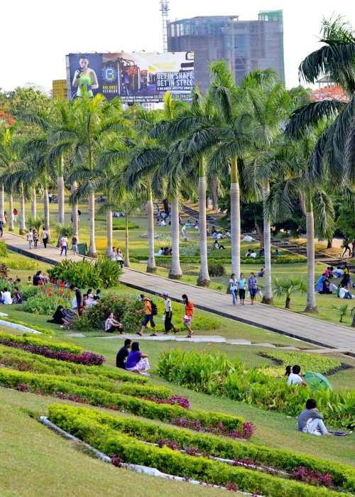 Green urban park with people walking.
