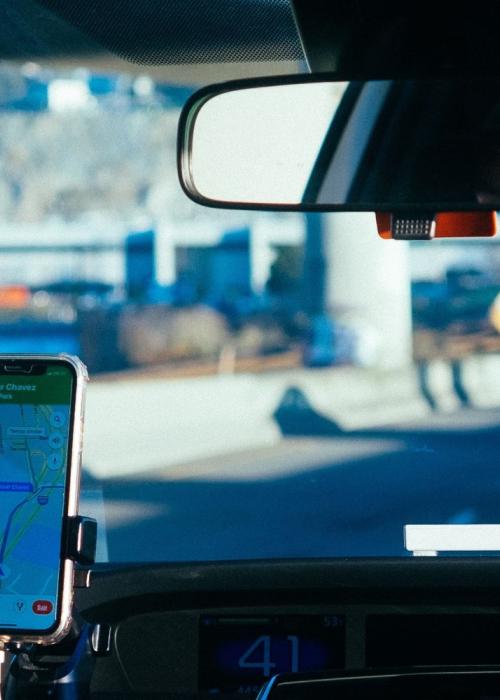 A driver following GPS directions on a mounted smartphone, taken from the backseat of the car.