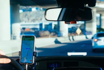 A driver following GPS directions on a mounted smartphone, taken from the backseat of the car.