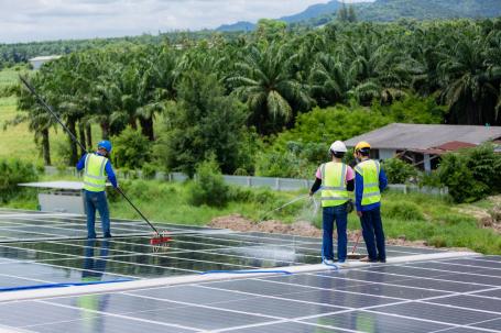 Workers clean dirt off a solar panel in Brazil