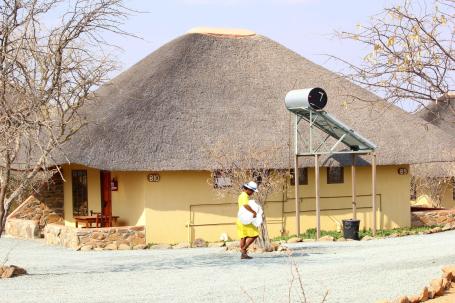 A person walks by a solar panel used to provide energy for a bungalow in Kamajab, Namibia.