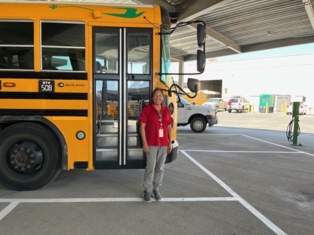 Bus driver Margarita Villalobos standing in front of her electric school bus.