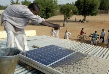 Boy washing rooftop solar panel.