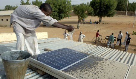 Boy washing rooftop solar panel.