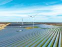 A landscape in England with fields of solar panels and wind turbines.