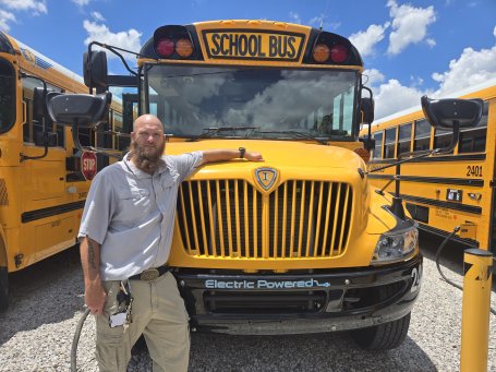 Bus driver Thomas Wondrock stands in front of his electric school bus