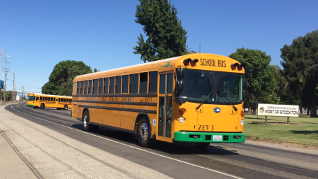 An electric school bus driving down a road.